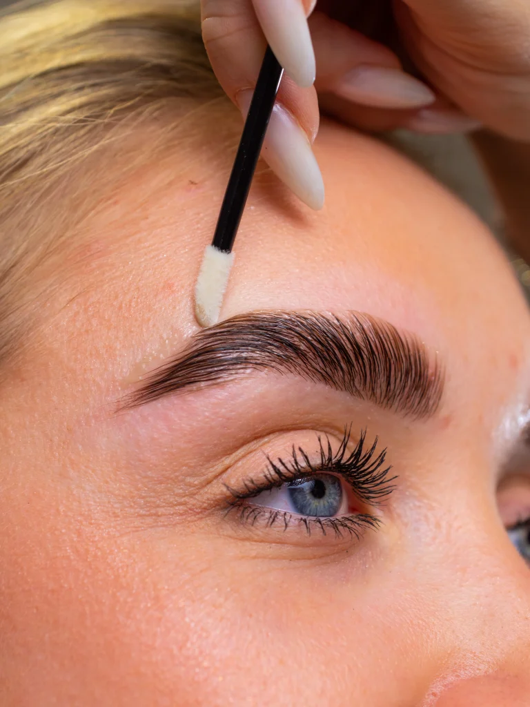 Szemöldök ápolása fehér applikátorral közeli beauty felvételen