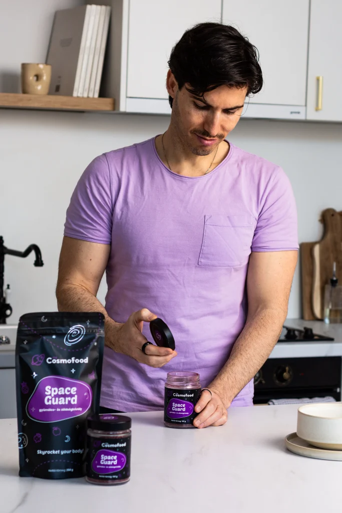 Férfi myCosmofood Space Guard üveget nyit ki konyhában, előtte Space Guard termékekkel