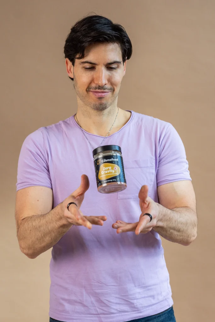 Férfi myCosmofood Zero Gravity+ üveget dob a levegőbe világos háttér előtt